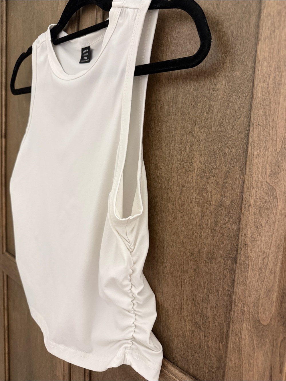 White high neck tank with cropped hem and ruched sides.
